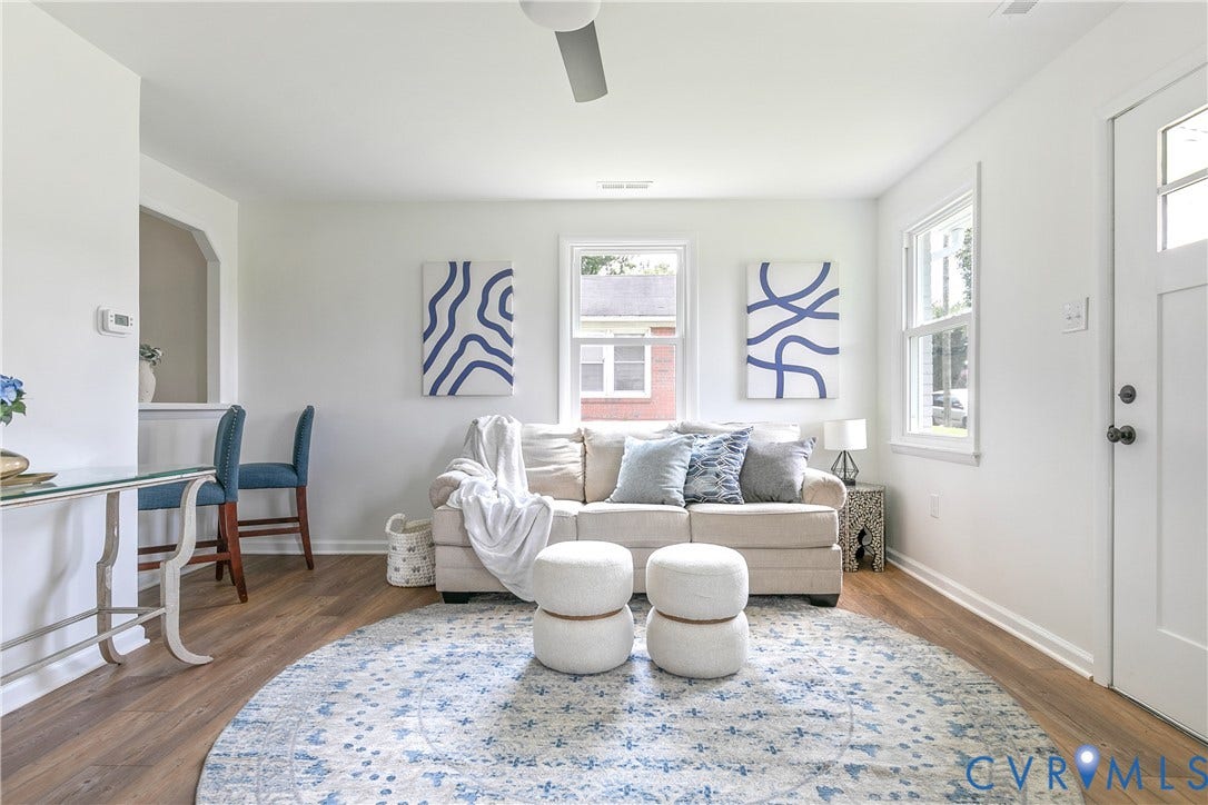 1809 Sussex Street, Whitcomb, Richmond, VA 23223 Open-concept interior featuring wood-finish flooring, crisp white wall finishes, a pass-through wall opening, and a multi-pane entry door