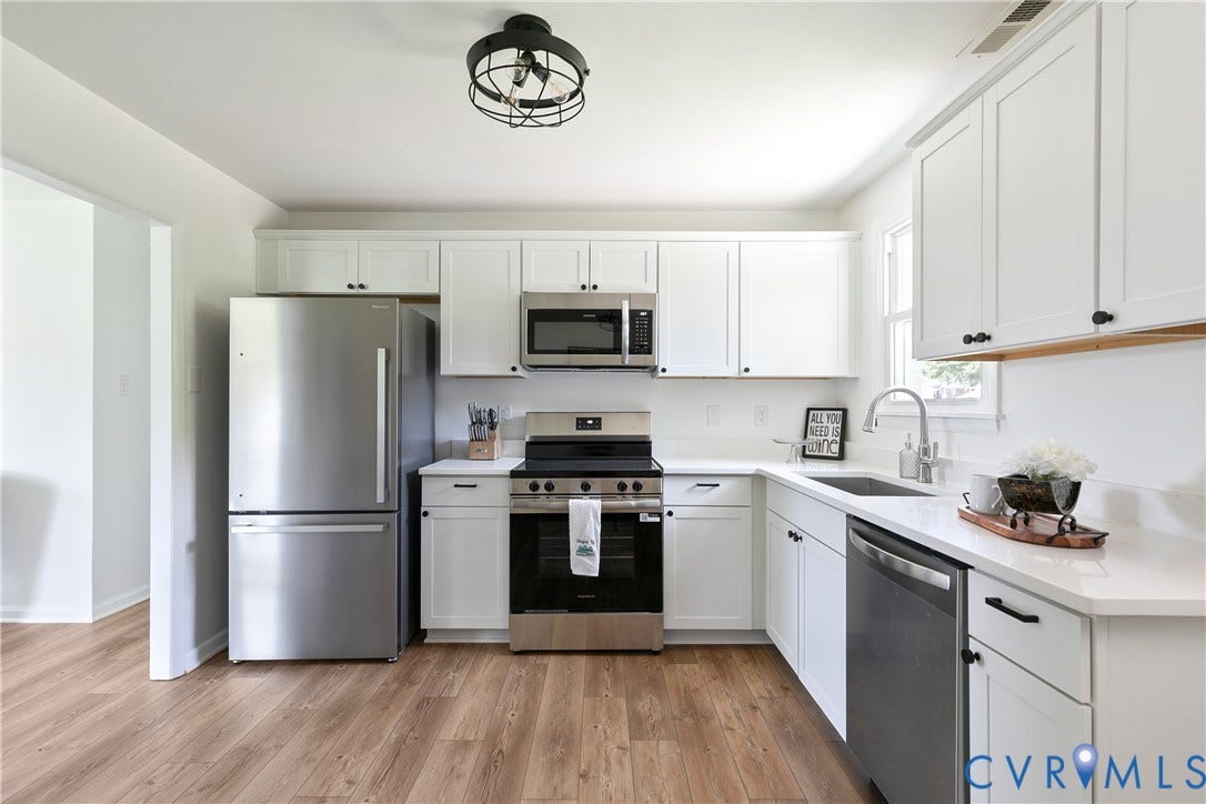 1809 Sussex Street, Whitcomb, Richmond, VA 23223 Kitchen featuring white shaker-style cabinetry, stainless steel appliances, white solid-surface countertops, wood-finish flooring, and a matte black geometric flush-mount light fixture