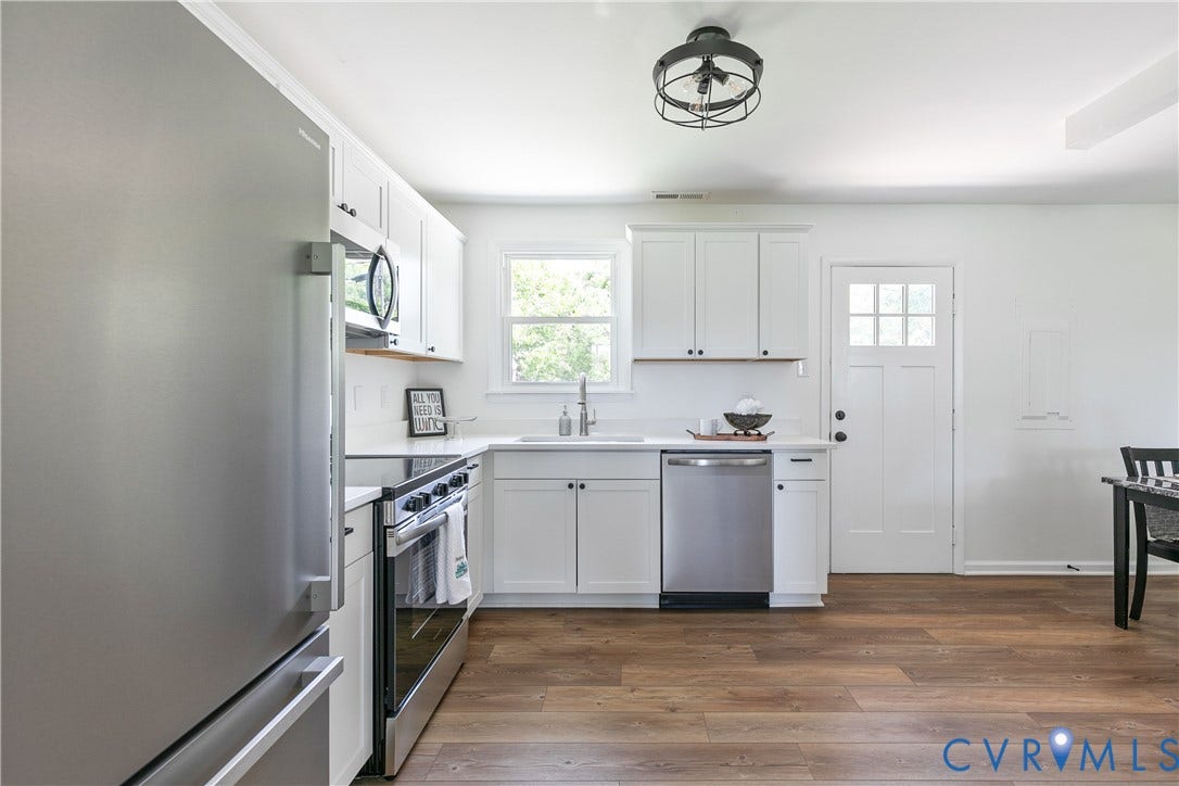 1809 Sussex Street, Whitcomb, Richmond, VA 23223 Kitchen featuring white shaker-style cabinetry, stainless steel appliances, wood-finish flooring, and a modern industrial-style ceiling fixture