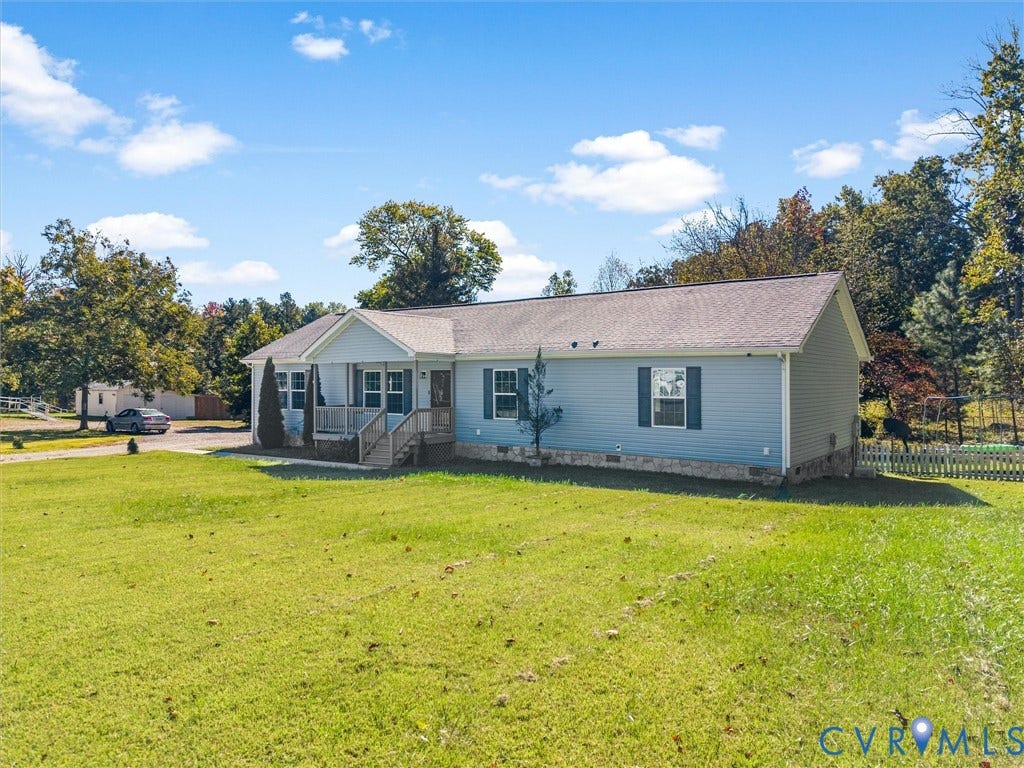 1625 Cedar Lane, Powhatan, VA 23139 Single-story home featuring light-blue horizontal siding, a gabled front porch, stone-veneer foundation accent, and a large open grass lawn