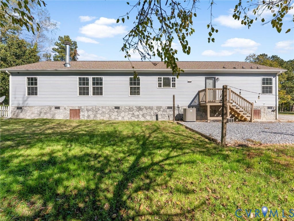 1625 Cedar Lane, Powhatan, VA 23139 Exterior rear facade featuring horizontal siding, stone-patterned foundation veneer, elevated wooden deck, and gravel parking area