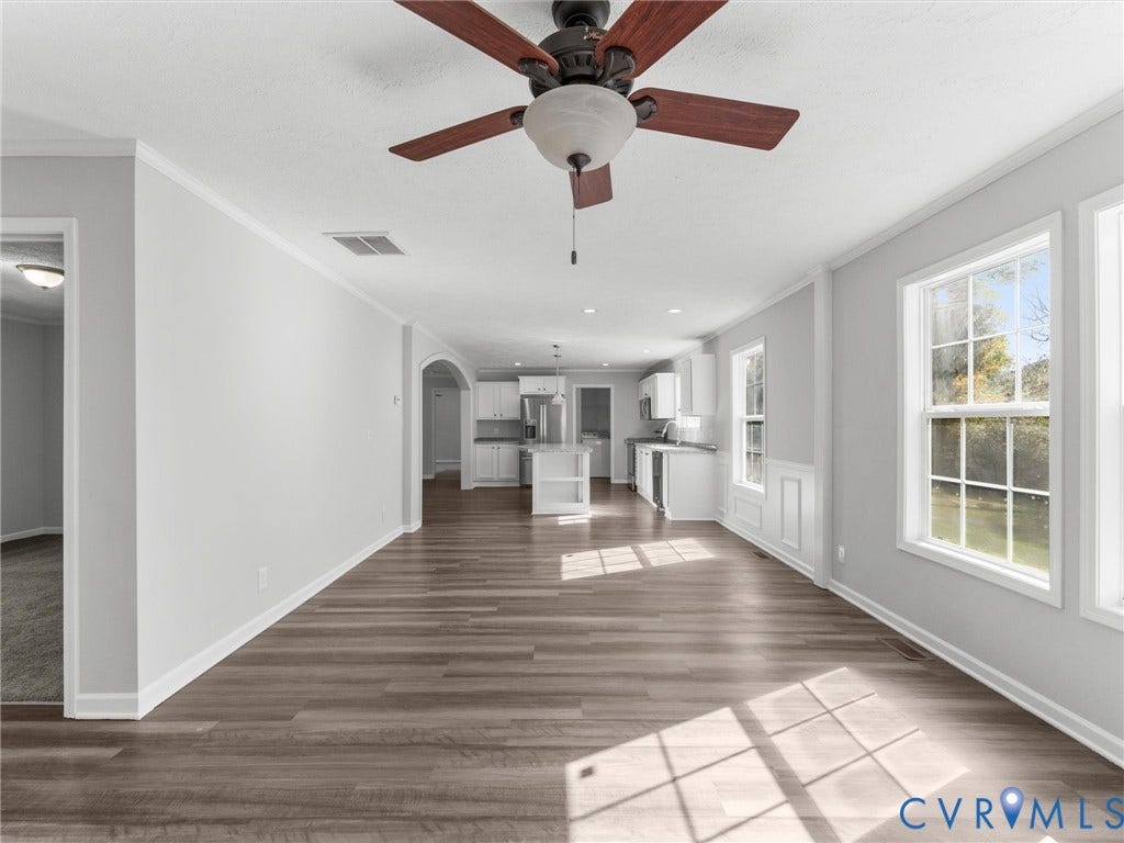 1625 Cedar Lane, Powhatan, VA 23139 Open-concept interior featuring wood-finish flooring, a central ceiling fan with integrated lighting, paneled wainscoting, and an arched entryway