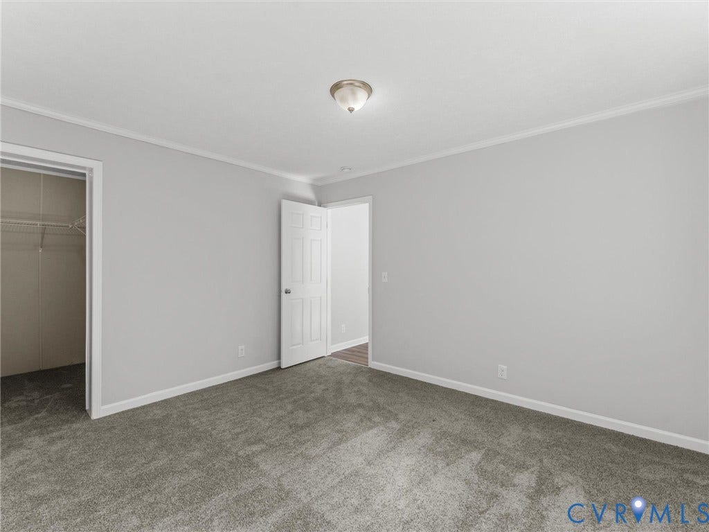 1625 Cedar Lane, Powhatan, VA 23139 Neutral-toned interior space featuring plush carpeting, crown molding, a multi-panel interior door, and a flush-mount ceiling light fixture