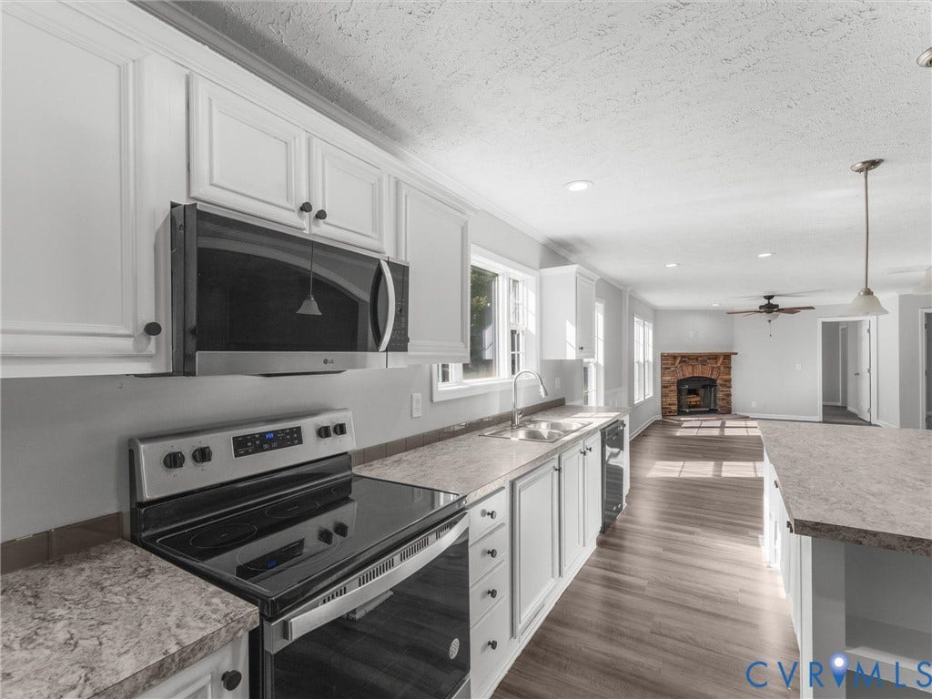 1625 Cedar Lane, Powhatan, VA 23139 Kitchen featuring white cabinetry, stone-patterned laminate countertops, stainless steel appliances, wood-finish flooring, and a stone fireplace
