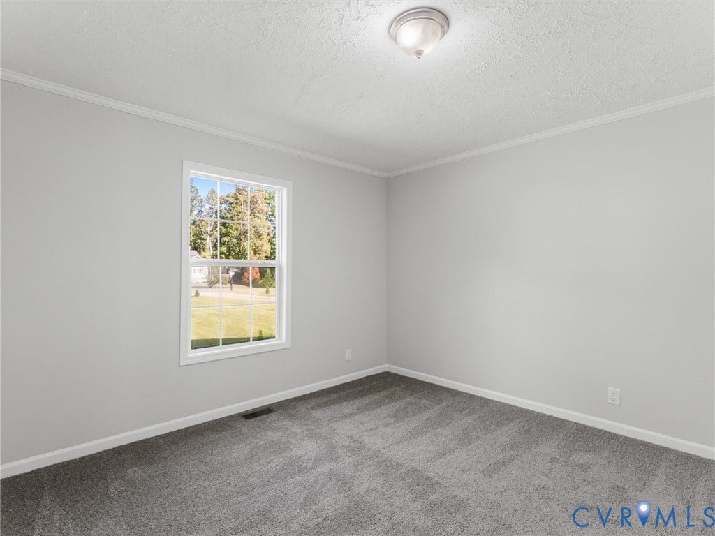 1625 Cedar Lane, Powhatan, VA 23139 Neutral-toned interior space featuring wall-to-wall carpeting, crown molding, a multi-pane grid window, and a flush-mount ceiling light fixture