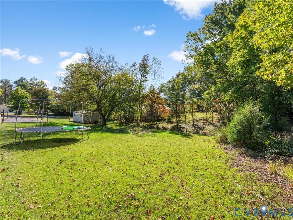 1625 Cedar Lane, Powhatan, VA 23139 Expansive backyard featuring a large grass lawn, mature trees, and a detached storage shed