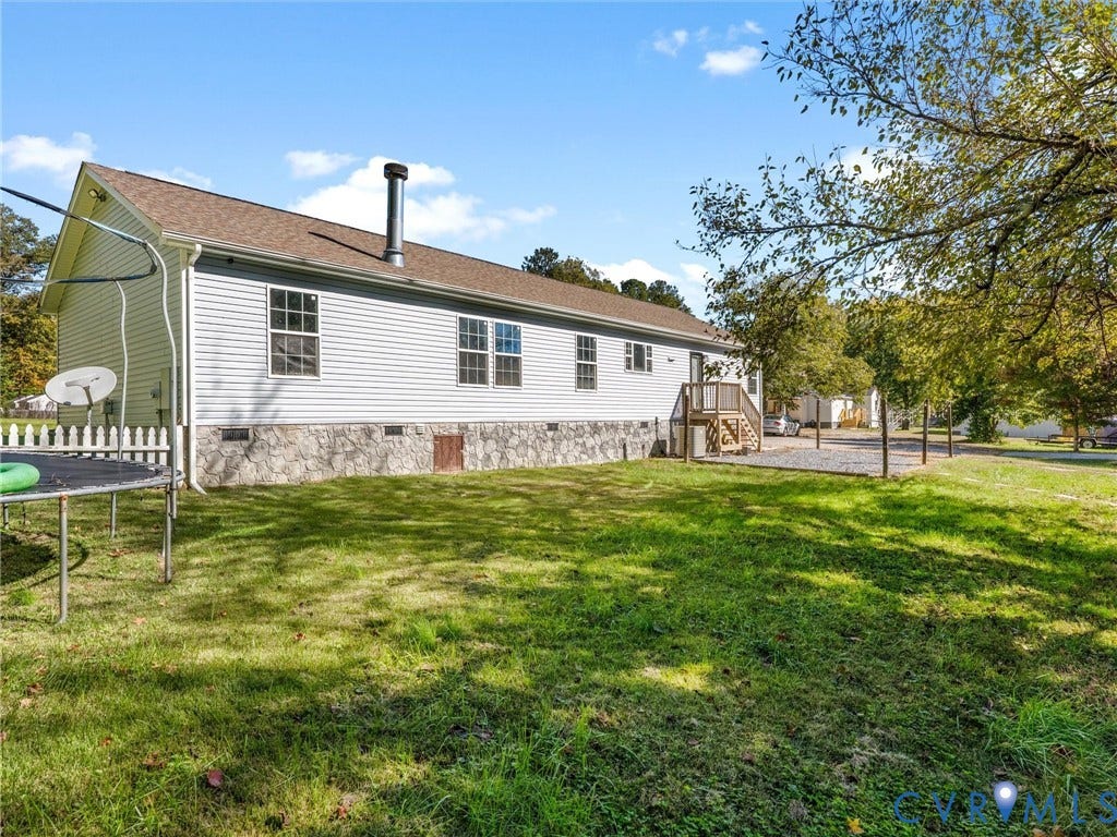 1625 Cedar Lane, Powhatan, VA 23139 Light-colored siding exterior with a masonry-finish foundation, asphalt shingle roof, exterior chimney, and rear wood deck