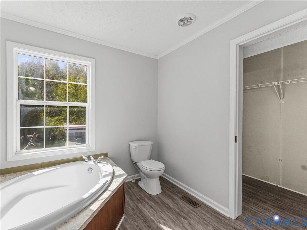 1625 Cedar Lane, Powhatan, VA 23139 Oval soaking tub with stone-composite surround, multi-pane window, wood-finish flooring, and walk-in closet with built-in shelving