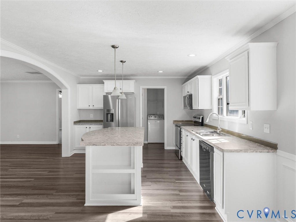 1625 Cedar Lane, Powhatan, VA 23139 Kitchen featuring white shaker-style cabinetry, an expansive center island, wood-finish flooring, stainless steel appliances, and an arched architectural opening