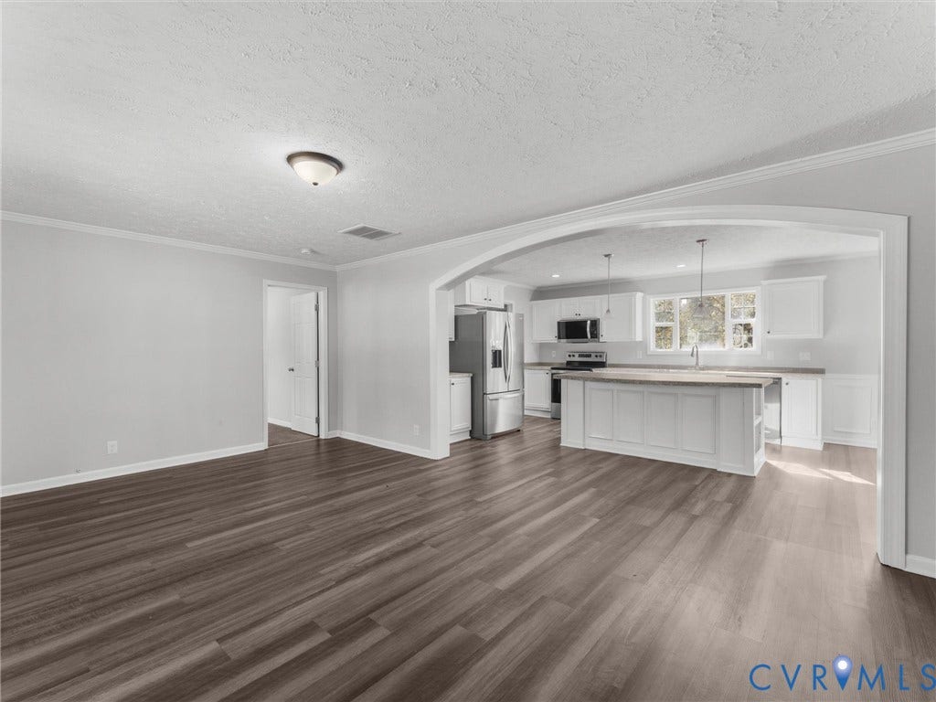 1625 Cedar Lane, Powhatan, VA 23139 Open interior space featuring arched structural molding, wood-finish flooring, white cabinetry, center island with stone-finish countertop, and stainless steel kitchen appliances