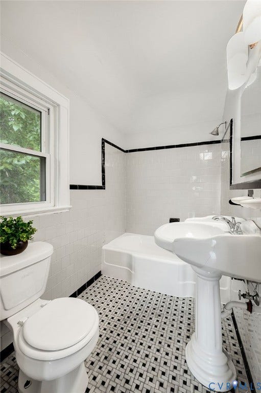602 N 39th Street, Chimborazo, Richmond, VA 23223 Bathroom featuring a porcelain pedestal sink, white subway tile wall surround with black accent trim, basketweave-pattern tile flooring, and a shower-tub combination