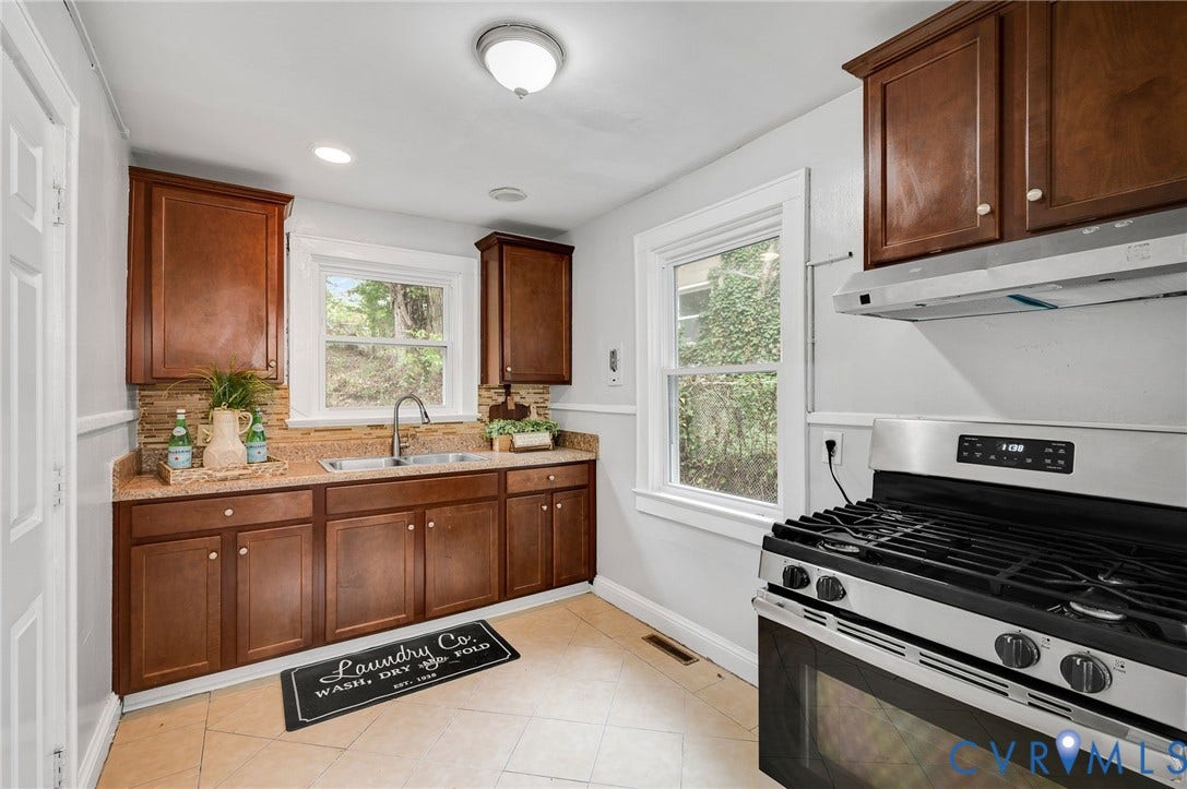 602 N 39th Street, Chimborazo, Richmond, VA 23223 Kitchen featuring stained-wood cabinetry, stone-texture countertops, tile backsplash, stainless steel gas range, and dual-basin stainless steel sink