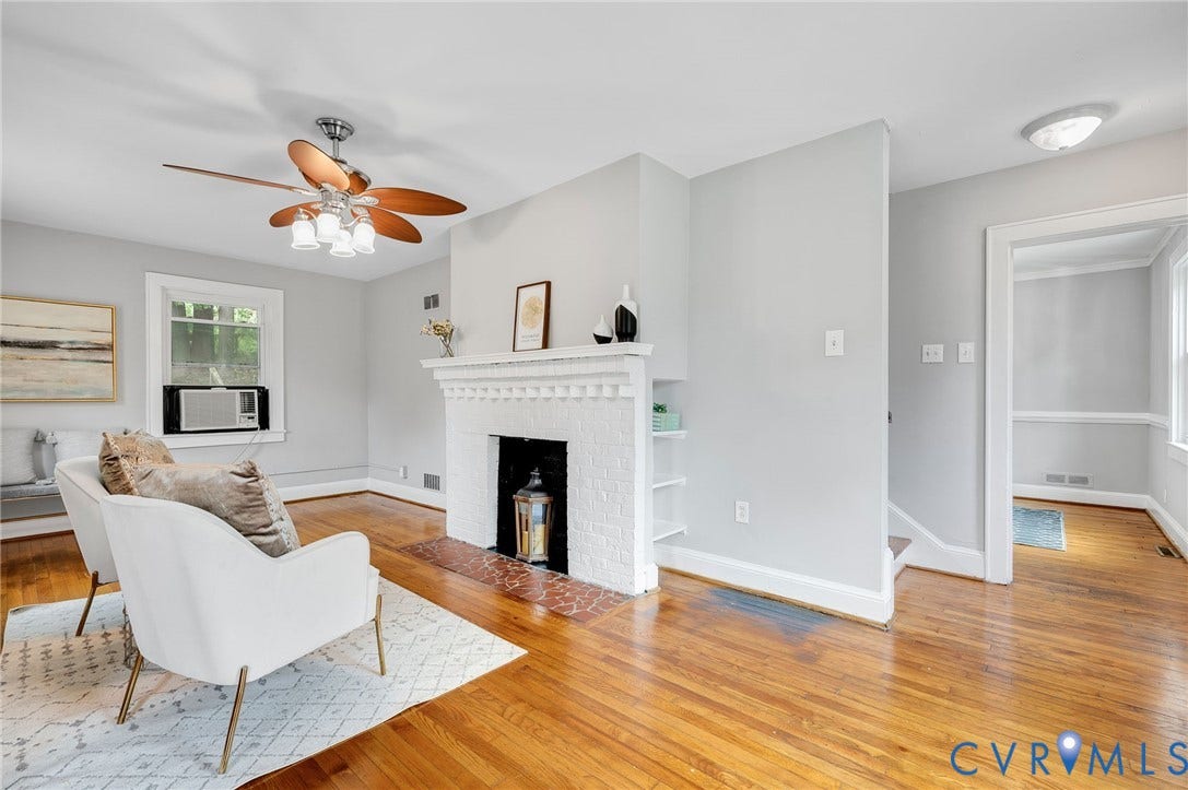 602 N 39th Street, Chimborazo, Richmond, VA 23223 Living room featuring wood-finish flooring, a painted brick fireplace with a decorative mantel, integrated wall shelving, and a ceiling fan with multi-blade design