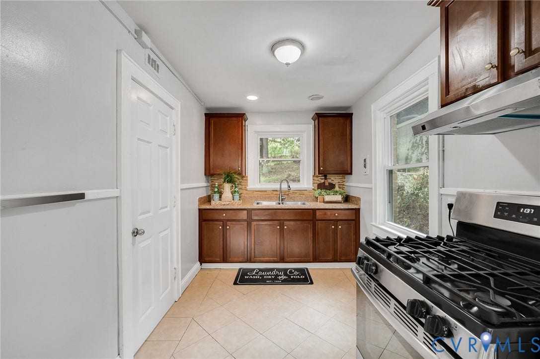 602 N 39th Street, Chimborazo, Richmond, VA 23223 Kitchen featuring stained wood cabinetry, stone-finish countertops, stainless steel gas range with overhead vent hood, tile flooring, and a double-basin sink