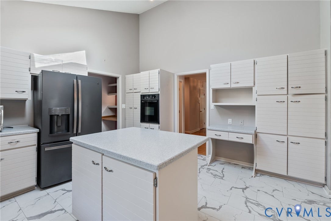 10862 Walton Lake Road, Dick Woods Subdivision, Disputanta, VA 23842 Kitchen featuring white horizontal-paneled cabinetry, a center island with a stone-composite countertop, floor-to-ceiling cabinetry, a built-in wall oven, and light-toned stone-finish flooring with grey veining