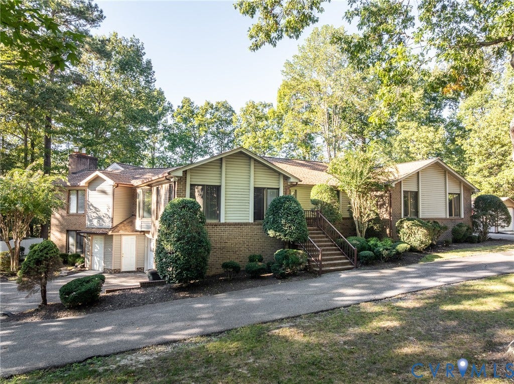 10862 Walton Lake Road, Dick Woods Subdivision, Disputanta, VA 23842 Multi-level exterior featuring a brick and siding facade, an elevated staircase with metal railing, an attached garage, and an asphalt driveway
