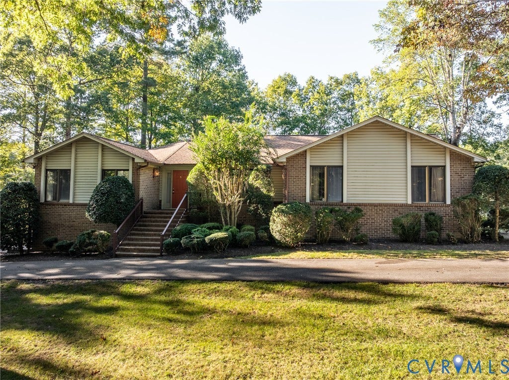 10862 Walton Lake Road, Dick Woods Subdivision, Disputanta, VA 23842 Exterior facade featuring brick masonry and siding, elevated entryway with staircase, and landscaped grounds with mature trees