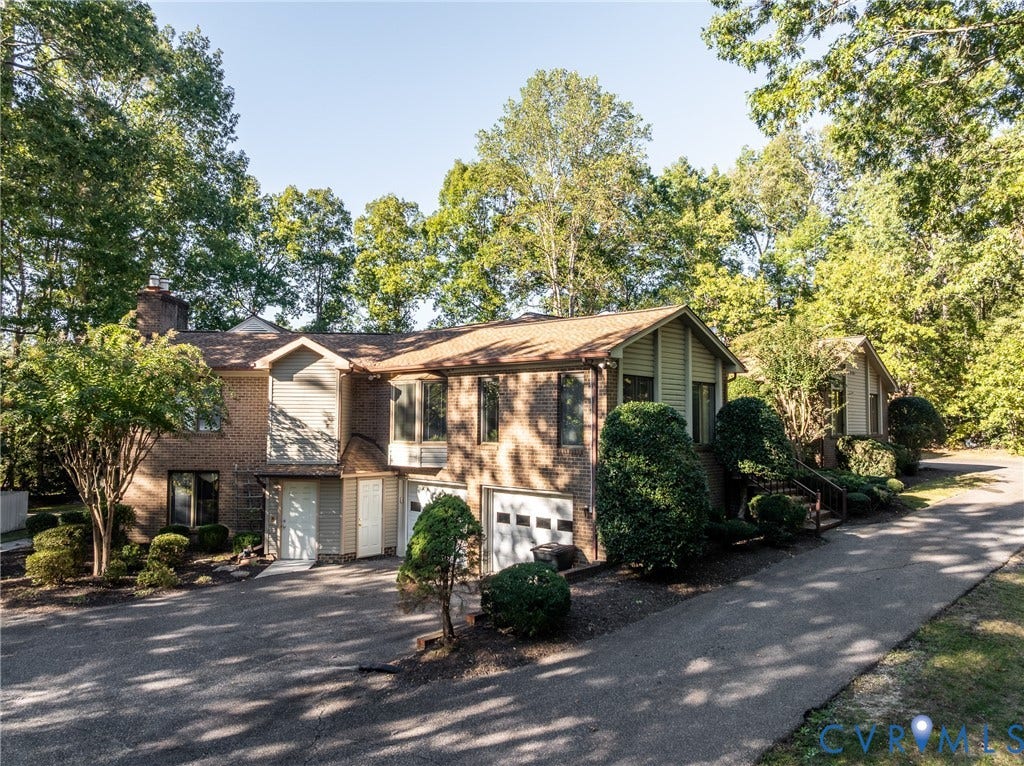 10862 Walton Lake Road, Dick Woods Subdivision, Disputanta, VA 23842 Multi-level exterior featuring a brick and siding facade, asphalt-paved driveway, integrated two-car garage, and established perimeter landscaping