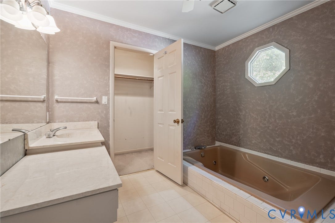10862 Walton Lake Road, Dick Woods Subdivision, Disputanta, VA 23842 Bathroom featuring a jetted soaking tub with tiled surround, octagonal window, vanity with stone-finish countertop, and walk-in closet