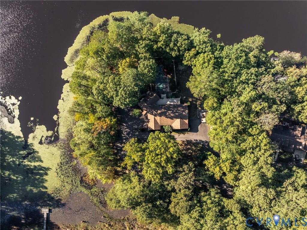 10862 Walton Lake Road, Dick Woods Subdivision, Disputanta, VA 23842 Aerial perspective of waterfront property featuring extensive mature tree coverage, a shingled roof, a paved driveway, and a private dock