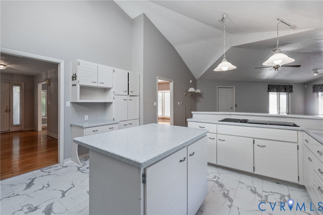 10862 Walton Lake Road, Dick Woods Subdivision, Disputanta, VA 23842 Kitchen featuring a vaulted ceiling, stone-patterned tile flooring, white cabinetry, a center island with a solid surface countertop, and dual pendant light fixtures