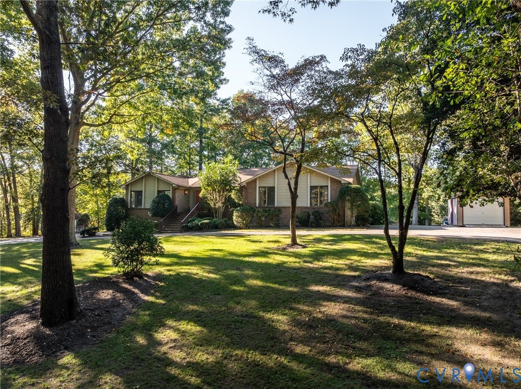 10862 Walton Lake Road, Dick Woods Subdivision, Disputanta, VA 23842 Exterior featuring a brick and siding facade, covered front entryway, expansive front lawn, mature canopy trees, and a detached garage
