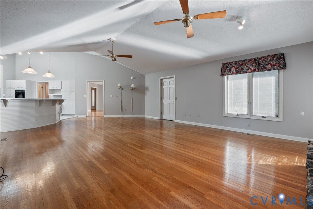 10862 Walton Lake Road, Dick Woods Subdivision, Disputanta, VA 23842 Vaulted ceilings with dual ceiling fans, expansive wood-finish flooring, and a wrap-around kitchen peninsula featuring white cabinetry