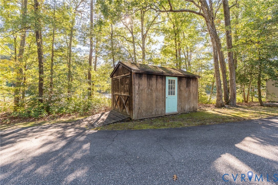 10862 Walton Lake Road, Dick Woods Subdivision, Disputanta, VA 23842 Exterior storage structure featuring wood siding, an asphalt-shingle roof, an entry door with glass paneling, and an integrated access ramp, positioned on a paved surface