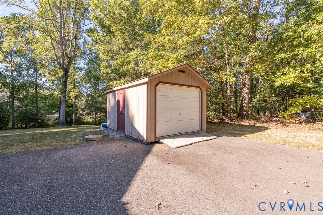 10862 Walton Lake Road, Dick Woods Subdivision, Disputanta, VA 23842 Detached shed with vertical siding, gable roof, roll-up garage door, side entry door, and paved access ramp