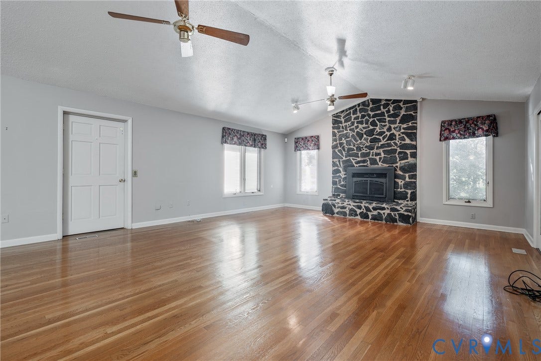 10862 Walton Lake Road, Dick Woods Subdivision, Disputanta, VA 23842 Vaulted ceilings with dual ceiling fans, wood-finish flooring, and a stone-clad floor-to-ceiling fireplace featuring a built-in firebox