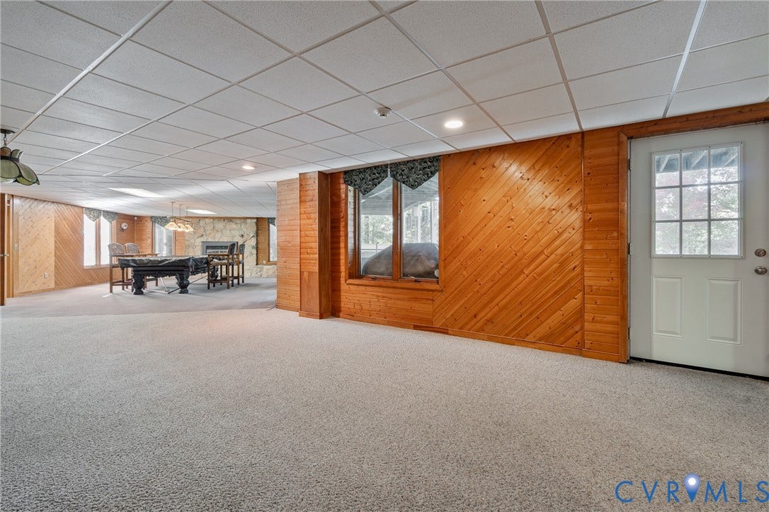 10862 Walton Lake Road, Dick Woods Subdivision, Disputanta, VA 23842 Wood-paneled wall accents, stone-faced fireplace, drop ceiling, carpeted flooring, and glass-paneled exterior door