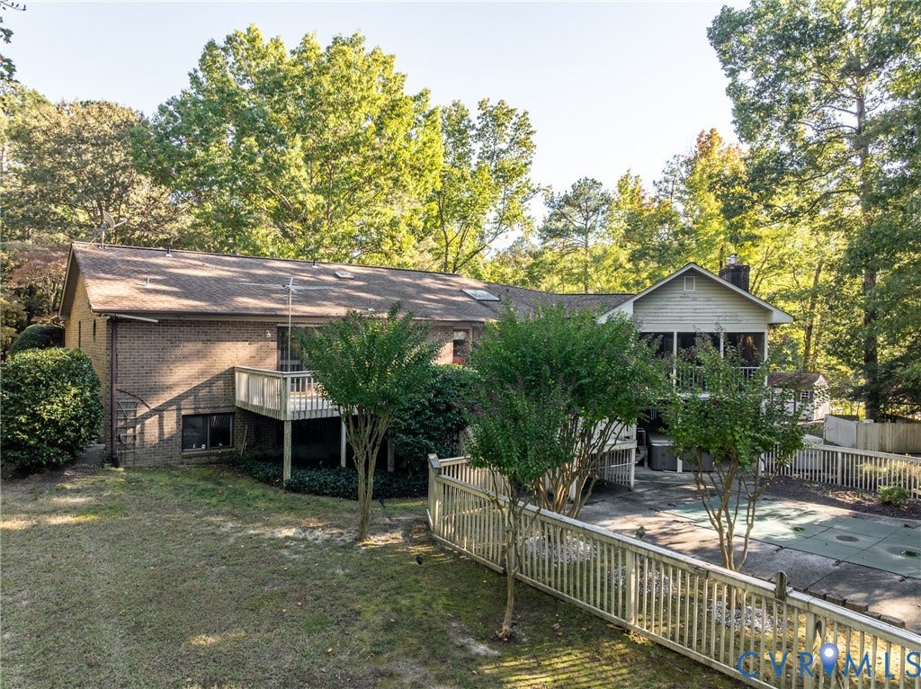 10862 Walton Lake Road, Dick Woods Subdivision, Disputanta, VA 23842 Brick exterior featuring a multi-level wooden deck, screened porch, fenced swimming pool area, and mature perimeter trees