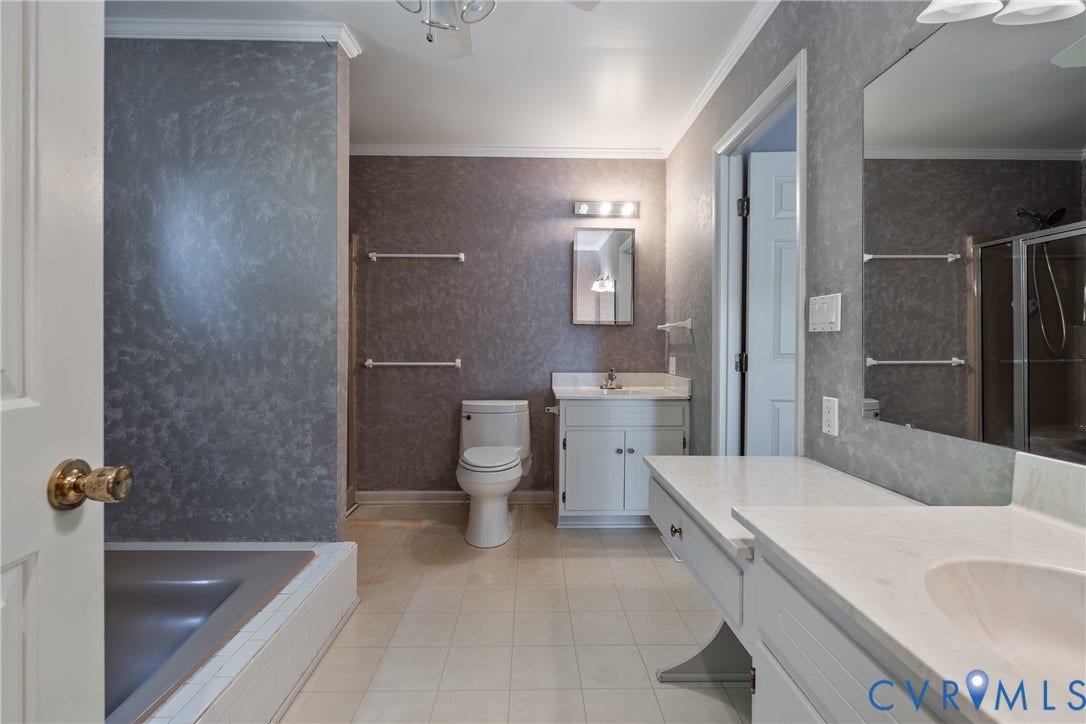 10862 Walton Lake Road, Dick Woods Subdivision, Disputanta, VA 23842 Bathroom featuring a built-in vanity with a solid-surface countertop, an integrated sink, an oversized wall-mounted mirror, and a tiled tub surround