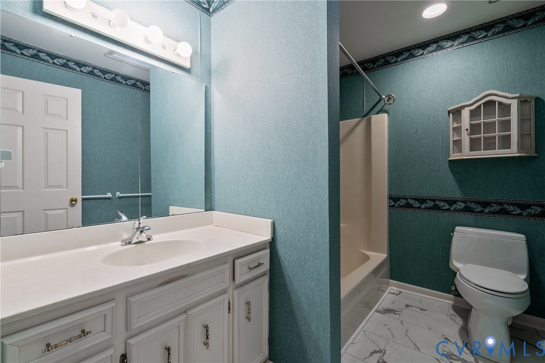 10862 Walton Lake Road, Dick Woods Subdivision, Disputanta, VA 23842 Bathroom featuring a vanity with white cabinetry and a solid-surface countertop, an integrated sink with a chrome faucet, a wall-mounted medicine cabinet, and stone-finish tile flooring