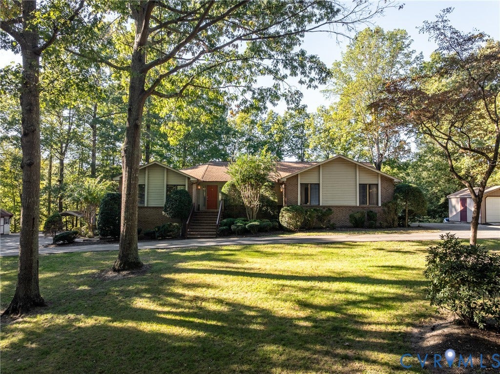 10862 Walton Lake Road, Dick Woods Subdivision, Disputanta, VA 23842 Exterior featuring a brick and siding facade, covered front entry with stairs, expansive lawn, mature trees, and a detached garage