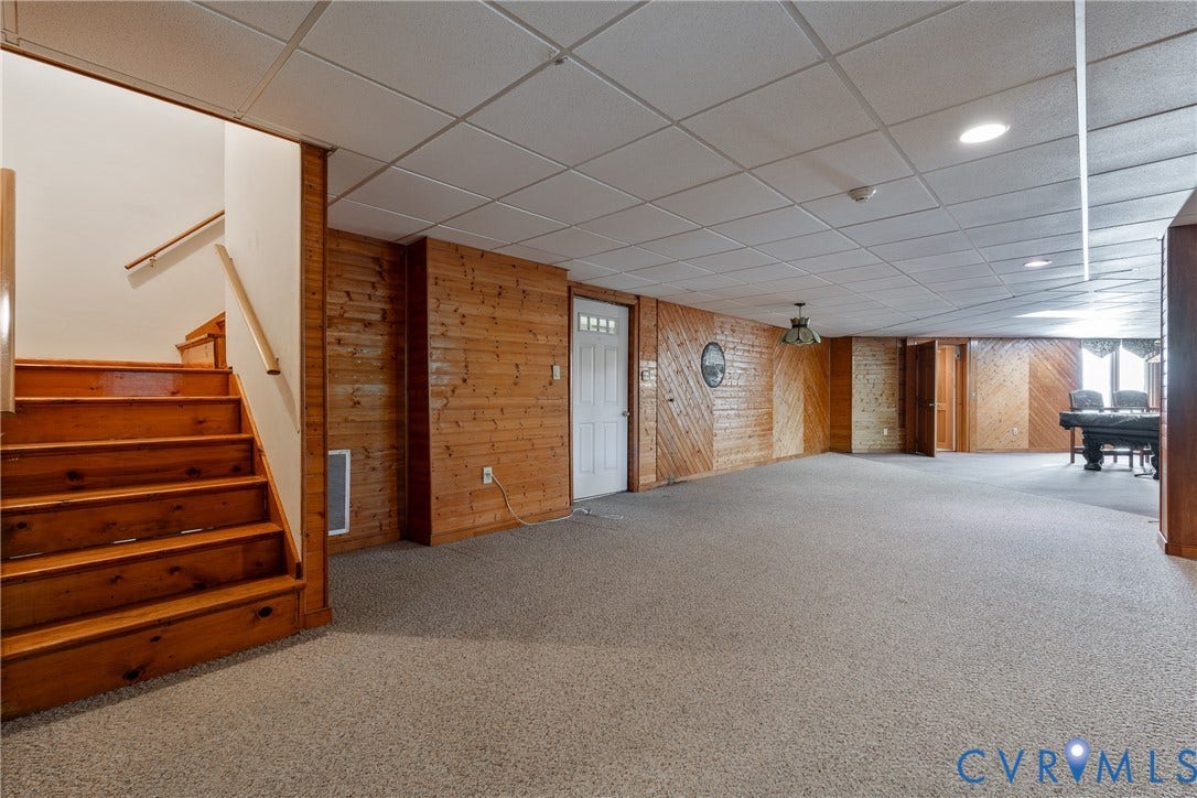 10862 Walton Lake Road, Dick Woods Subdivision, Disputanta, VA 23842 Finished room featuring wood-paneled walls, carpeted flooring, a dropped ceiling with recessed lighting, and wooden staircase with handrail