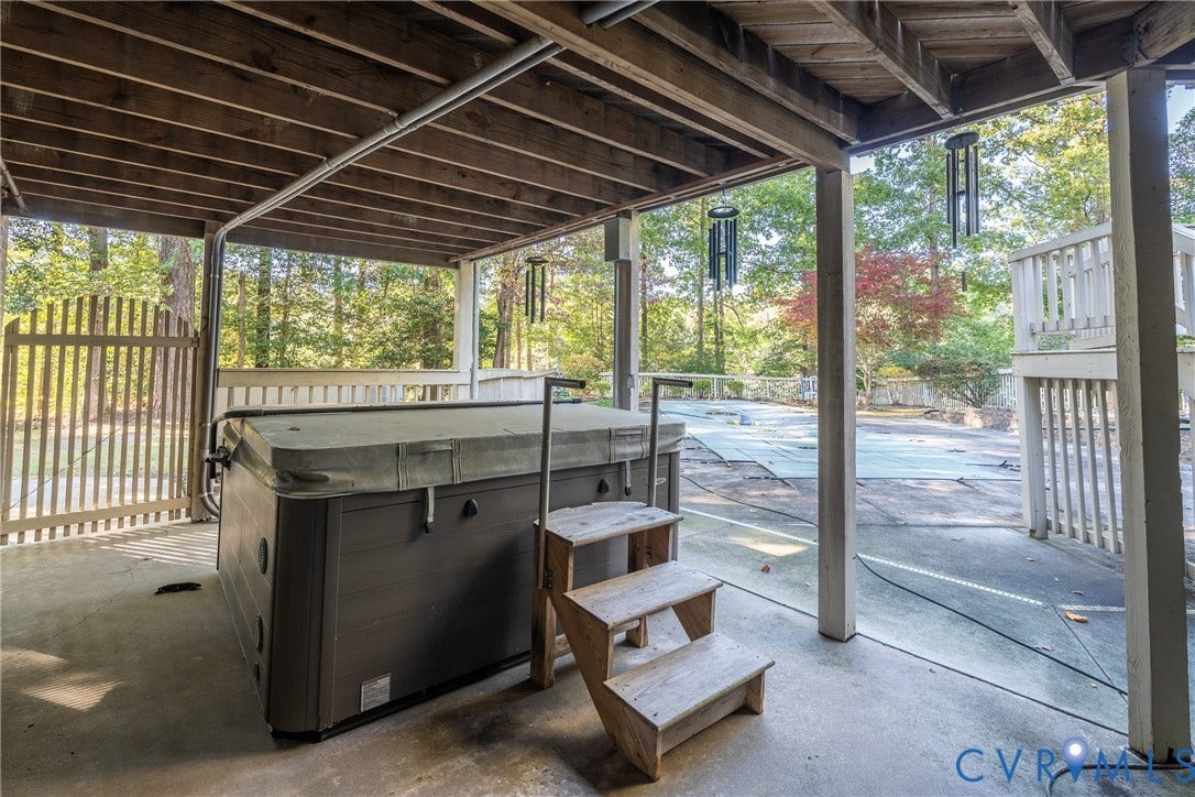 10862 Walton Lake Road, Dick Woods Subdivision, Disputanta, VA 23842 Covered concrete patio featuring a built-in hot tub with stairs, vertical wood-slat fencing, and a fenced swimming pool area