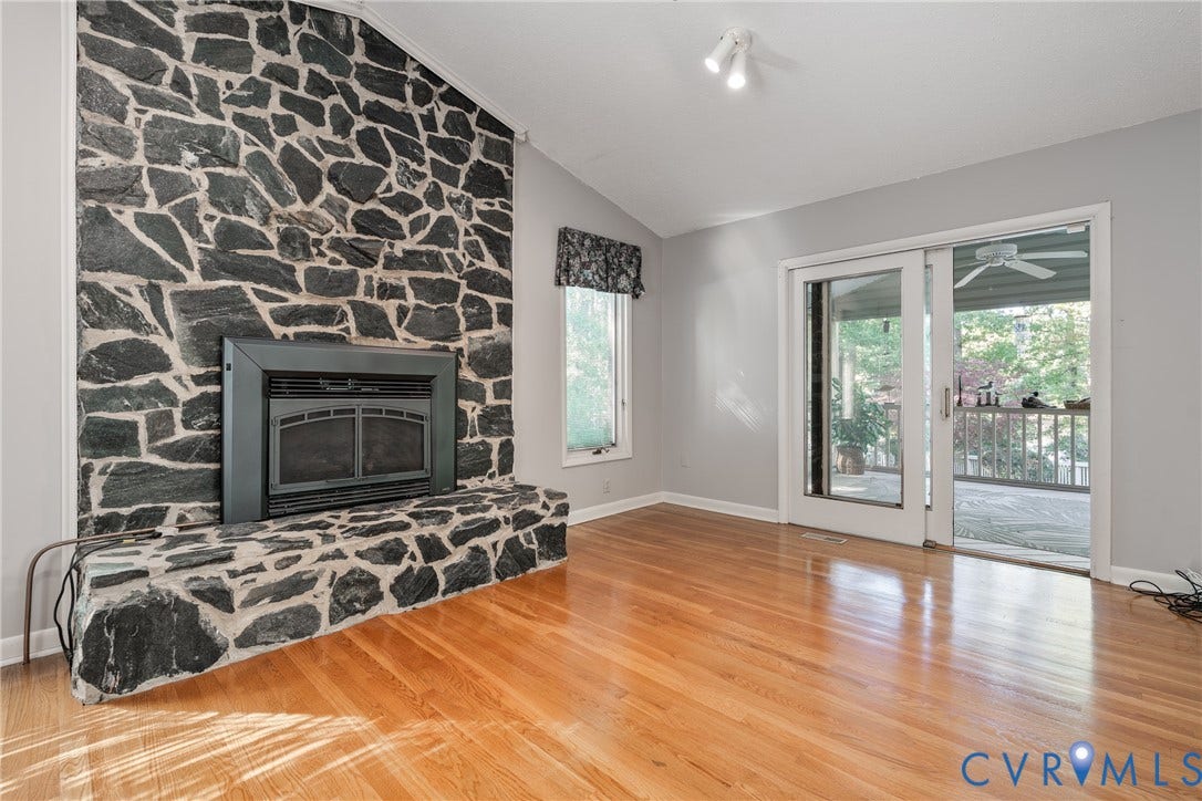 10862 Walton Lake Road, Dick Woods Subdivision, Disputanta, VA 23842 Floor-to-ceiling stone fireplace, wood-finish flooring, vaulted ceiling, and sliding glass doors with access to an exterior deck