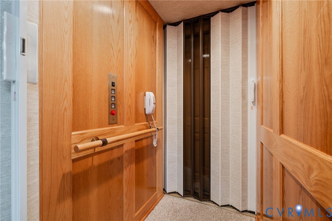 10862 Walton Lake Road, Dick Woods Subdivision, Disputanta, VA 23842 Interior elevator featuring wood paneling, a mounted control panel, a horizontal wooden grab bar, and a bi-fold folding door