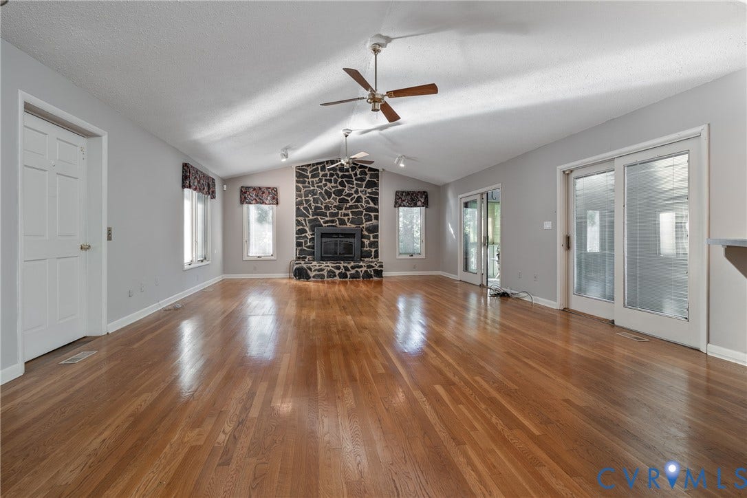 10862 Walton Lake Road, Dick Woods Subdivision, Disputanta, VA 23842 Vaulted ceilings featuring dual ceiling fans, stone-surround fireplace, wood-finish flooring, and multiple glass-paneled exterior doors