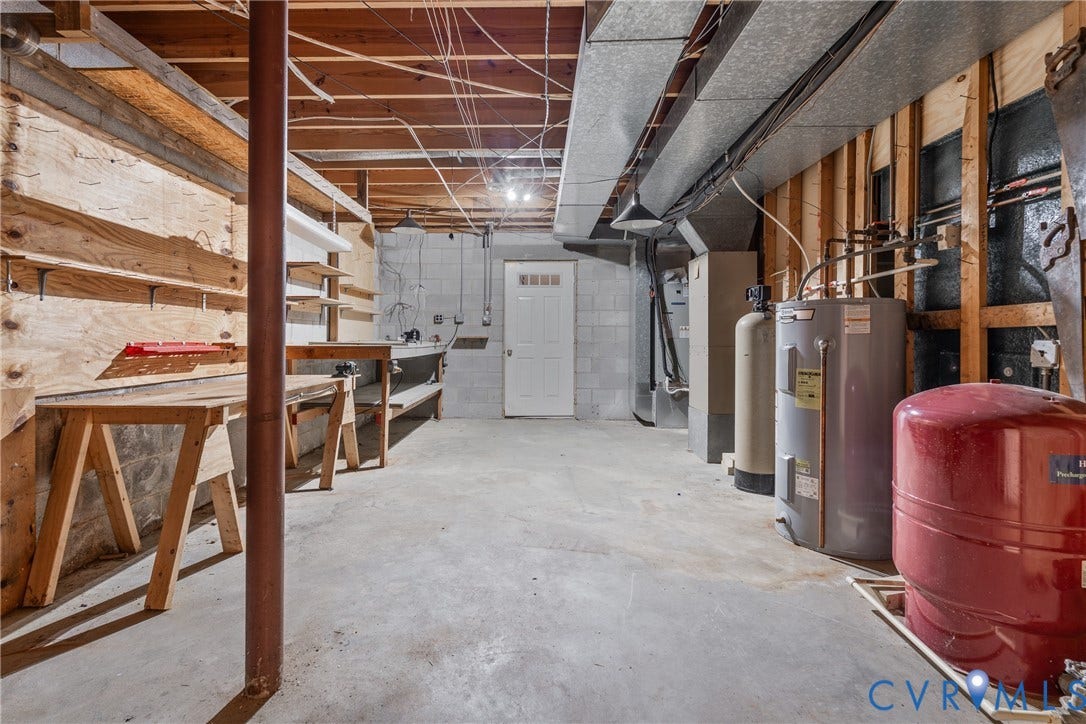 10862 Walton Lake Road, Dick Woods Subdivision, Disputanta, VA 23842 Lower-level utility area featuring exposed joist ceilings, concrete block walls, concrete flooring, built-in wooden shelving, and functional mechanical systems including a water heater and pressure tank
