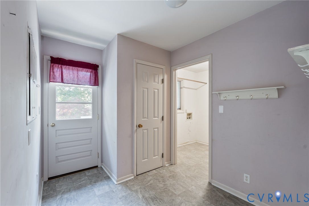 10862 Walton Lake Road, Dick Woods Subdivision, Disputanta, VA 23842 Utility room featuring resilient stone-finish flooring, a solid-panel door, and a built-in wall-mounted coat rack