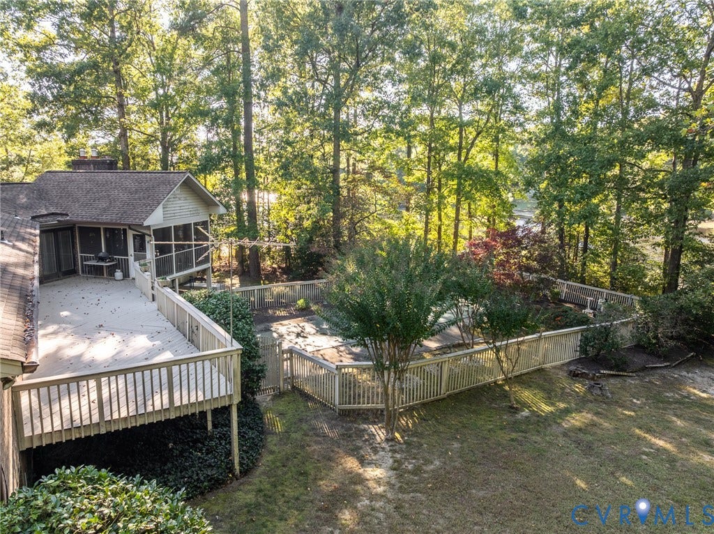 10862 Walton Lake Road, Dick Woods Subdivision, Disputanta, VA 23842 Elevated wooden deck with balustrade railings, screened-in porch, fenced-in pool area, and mature perimeter trees