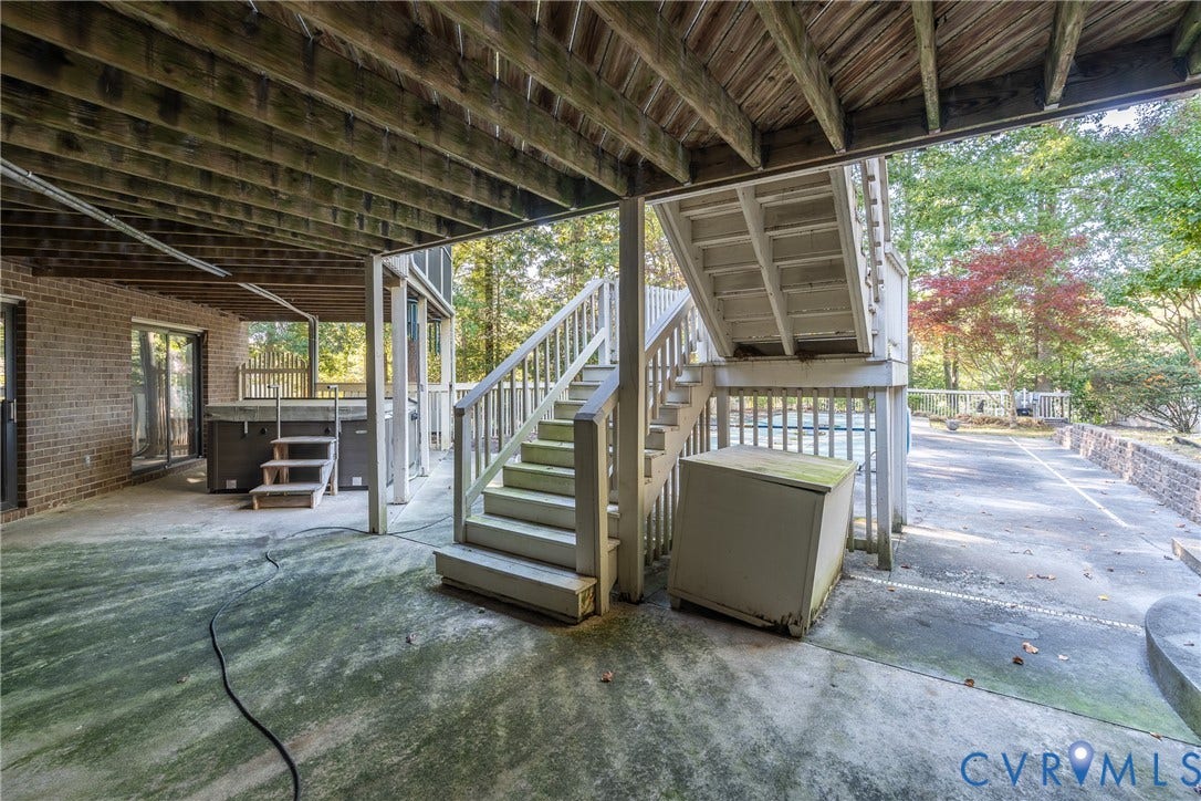 10862 Walton Lake Road, Dick Woods Subdivision, Disputanta, VA 23842 Covered concrete patio featuring brick exterior walls, wood-framed ceiling, stairs to the upper level, and a built-in hot tub