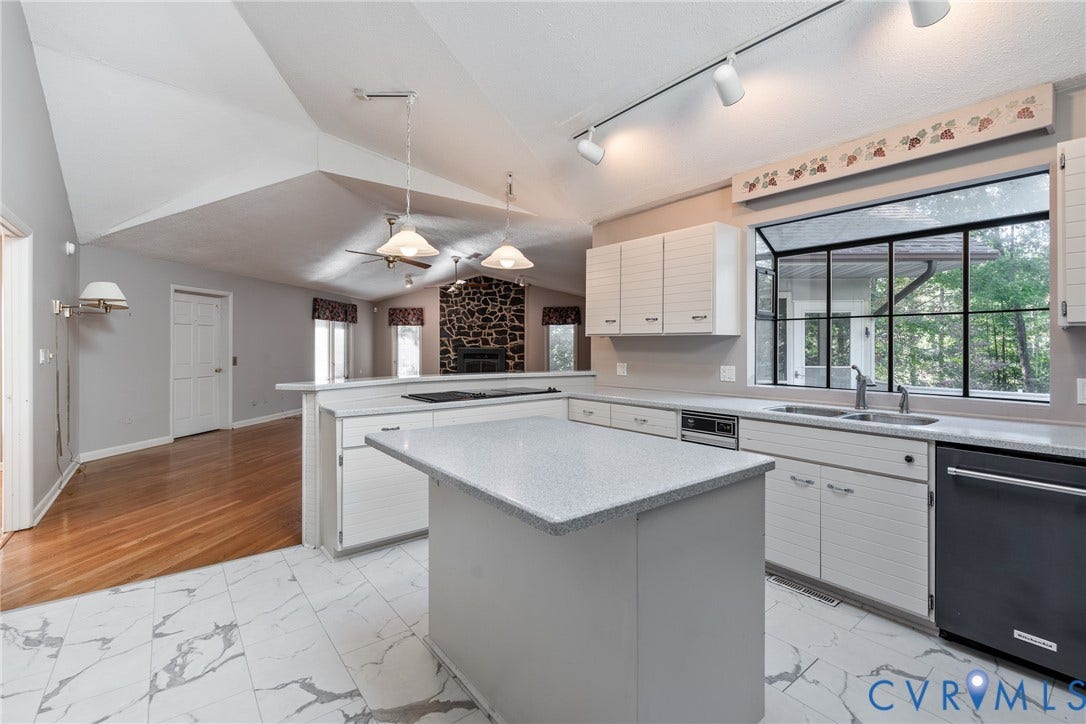 10862 Walton Lake Road, Dick Woods Subdivision, Disputanta, VA 23842 Kitchen featuring vaulted ceilings, a central island with a solid surface countertop, white horizontal-groove cabinetry, stone-clad fireplace surround, and wood-finish flooring