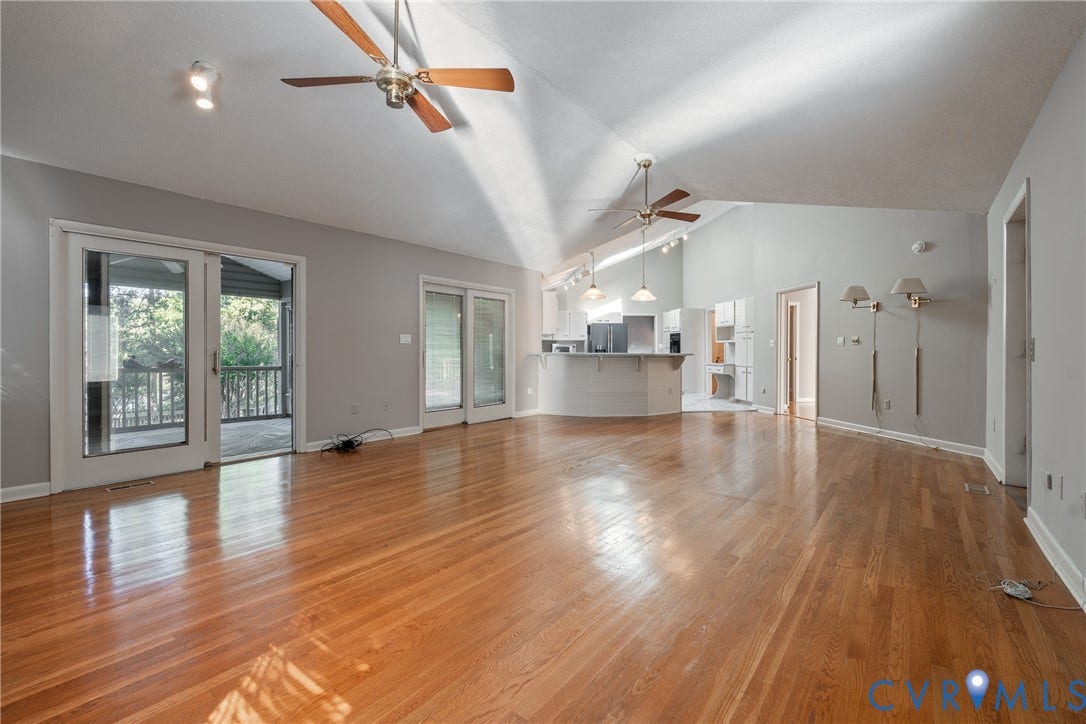 10862 Walton Lake Road, Dick Woods Subdivision, Disputanta, VA 23842 Open-concept interior featuring vaulted ceilings, wood-finish flooring, dual ceiling fans, sliding glass doors, and a built-in kitchen peninsula