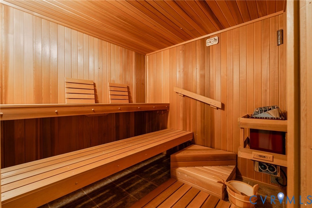 10862 Walton Lake Road, Dick Woods Subdivision, Disputanta, VA 23842 Sauna featuring wood paneling, multi-level built-in bench seating, integrated wall-mounted heater with rock basin, and wood-slat flooring