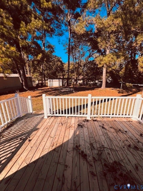 1525 Circle Drive, Petersburg, VA 23803 Wood-plank decking featuring white vinyl railing, encompassing a backyard with mature trees and a detached structure