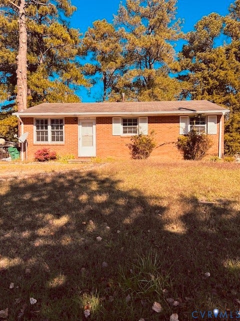 1525 Circle Drive, Petersburg, VA 23803 Single-story brick exterior featuring a gable roof, white window shutters, and a wood-surrounded lot with mature trees