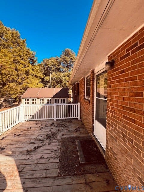 1525 Circle Drive, Petersburg, VA 23803 Elevated wood deck featuring white railing and red brick exterior wall with a storm door